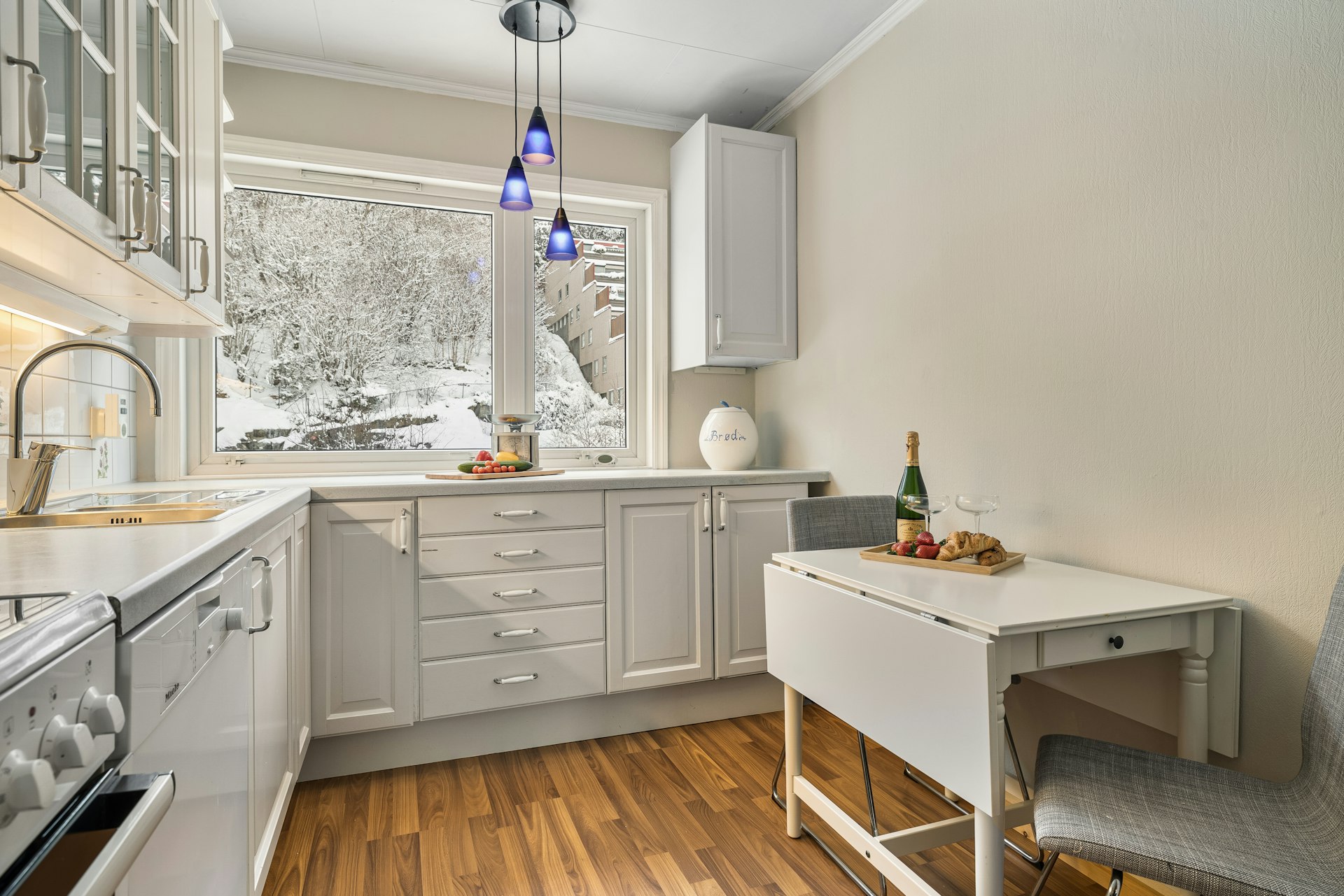 A kitchen with white cabinets and wooden floors